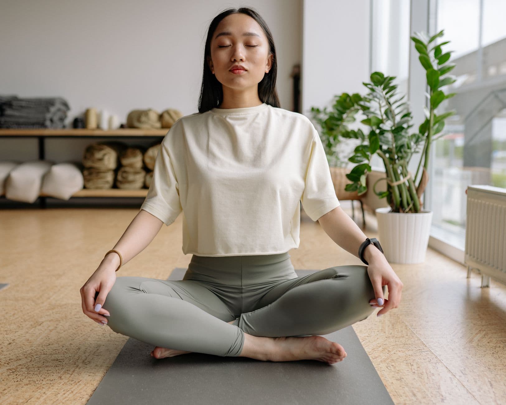 Femme assise au sol, mains posées sur les genoux, respiration calme en intérieur