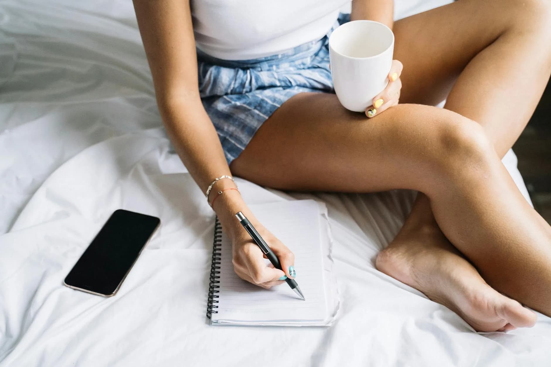 Entrepreneure assise à son bureau le matin, café et carnet ouvert, lumière douce, posture posée