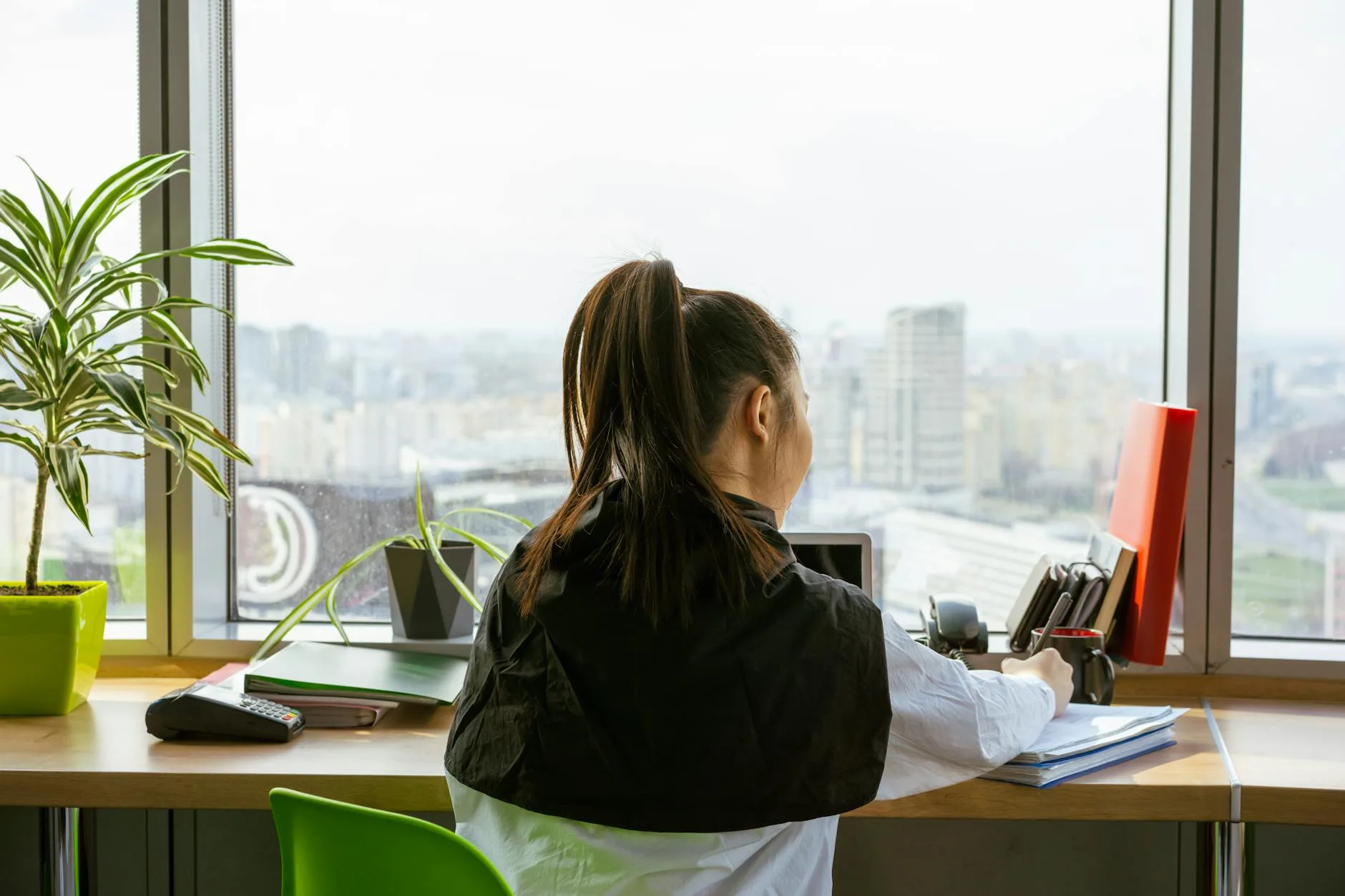 Femme prenant une pause respiration calme à son bureau près d'une fenêtre, lumière douce du matin