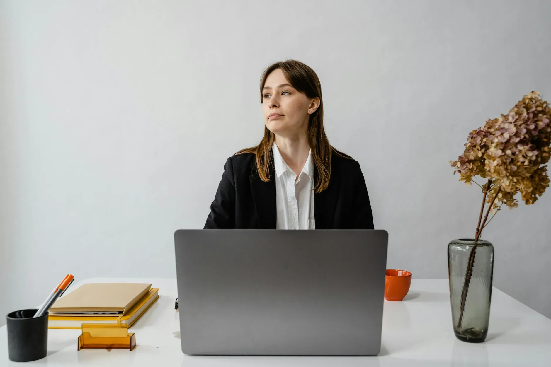 Femme entrepreneure pensive devant son ordinateur, lumière douce, posture posée mais hésitante