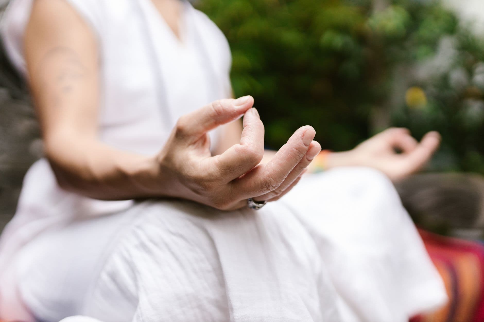 Personne en posture de méditation, mains en mudra, lumière douce du matin