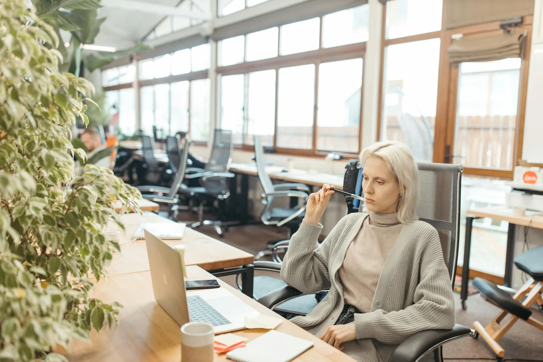 Femme méditant calmement assise à son bureau dans un open space lumineux, posture droite, yeux fermés