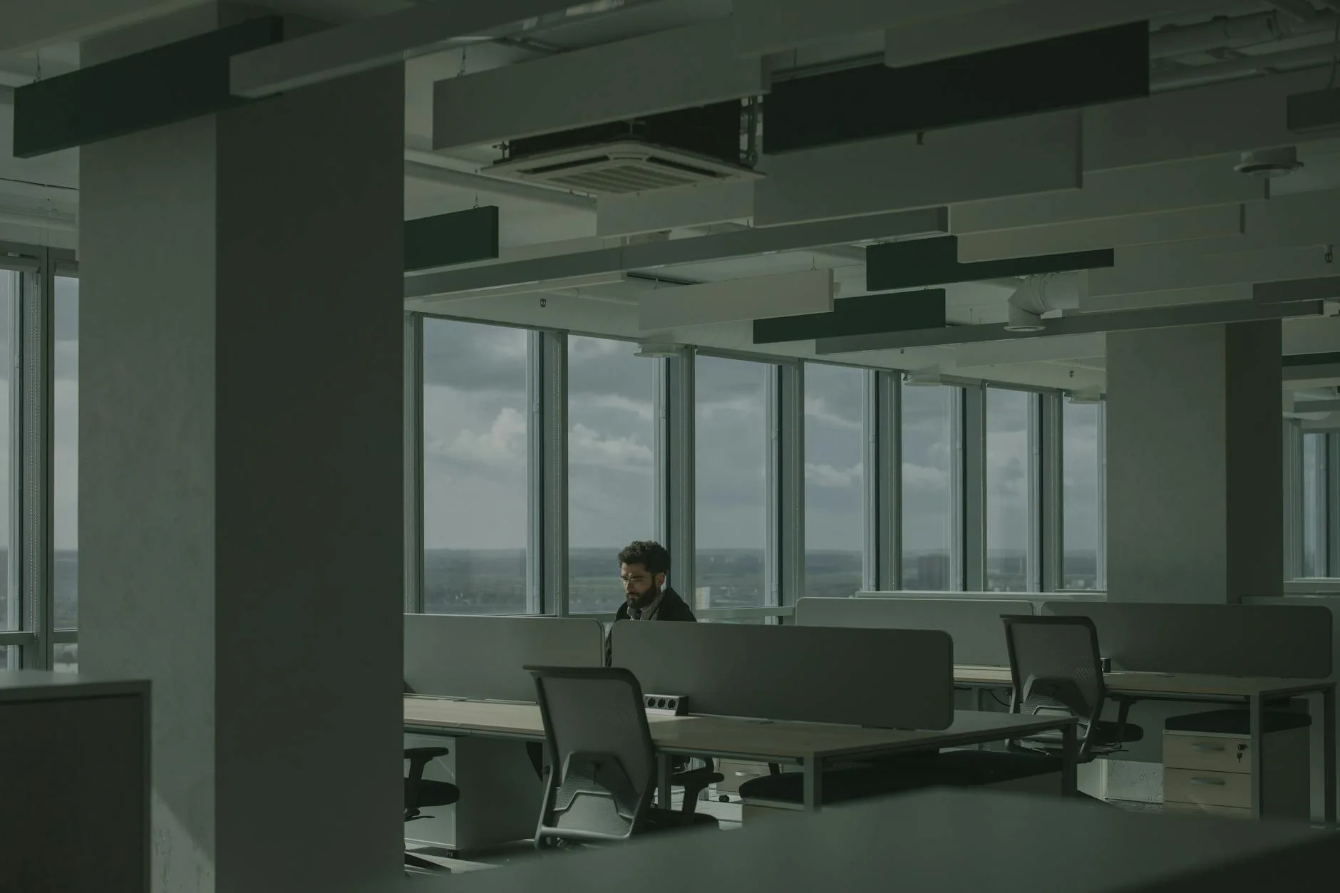 Femme à son bureau dans un open space lumineux, posture détendue, prenant une pause respiration